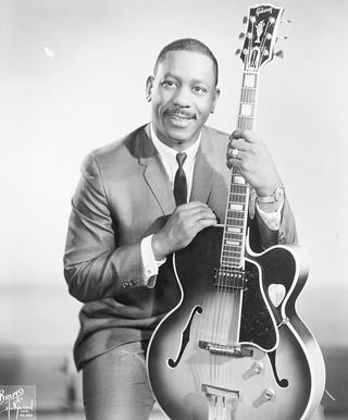 Wes Montgomery. Publicity handout of Wes Montgomery, jazz guitarist, pictured here sitting, holding guitar in front of him, smiling. Undated photograph