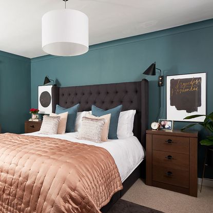 teal walled bedroom with carpet flooring and wooden bedside table