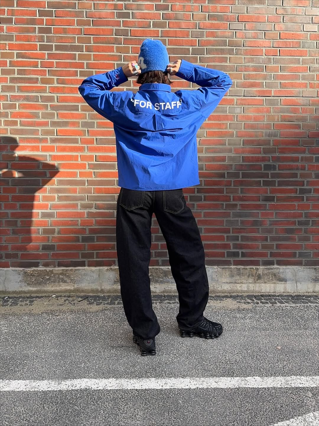 Leonie Charlott is photographed outside wearing Nike Shox TL trainers in black with a blue hat and jacket and black jeans.