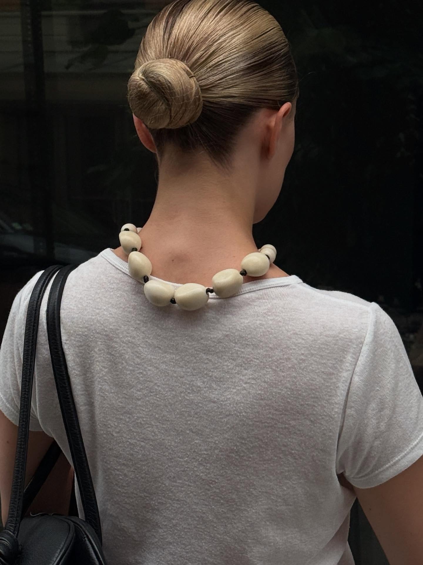 Christie wearing a chunky rock necklace with a white T-shirt