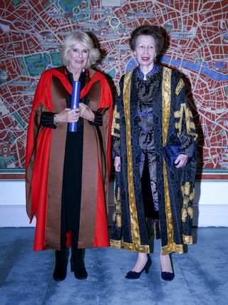 Queen Camilla holding a degree and Princess Anne wearing university robes