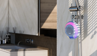 Tribit AquaEase Shower Bluetooth speaker in a shower, with the water running