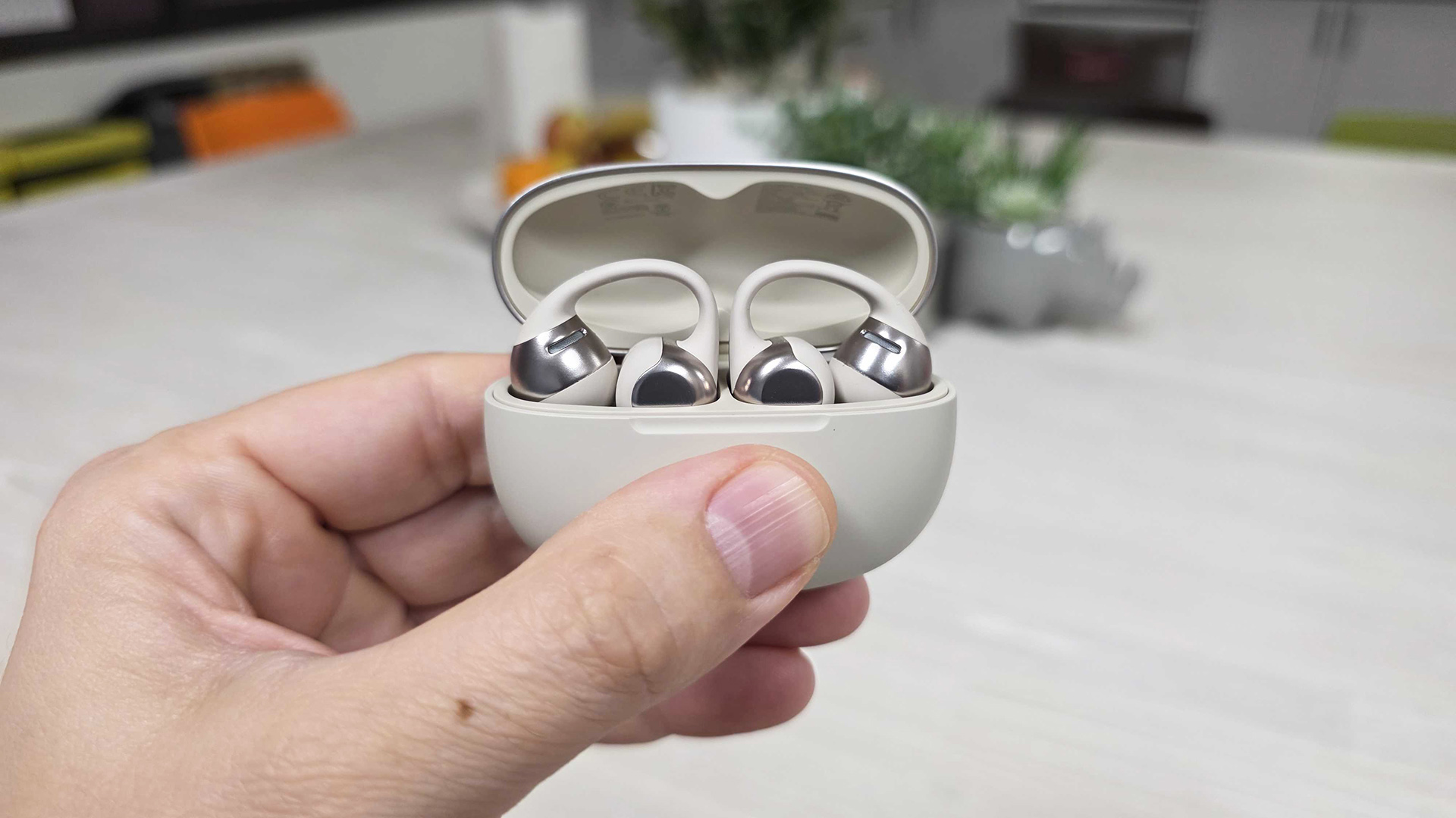 In-hand image of Shokz OpenDots One in charging case