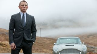 Daniel Craig stands near his Aston Martin DB5 in the countryside in Skyfall.