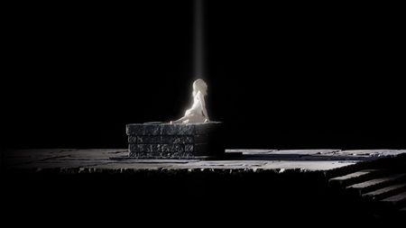 A young woman sits up on a stone dais, surrounded by darkness.