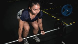 Woman performs a deadlift with a barbell