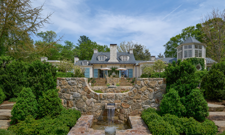 Large property with stone water feature and rill in foreground