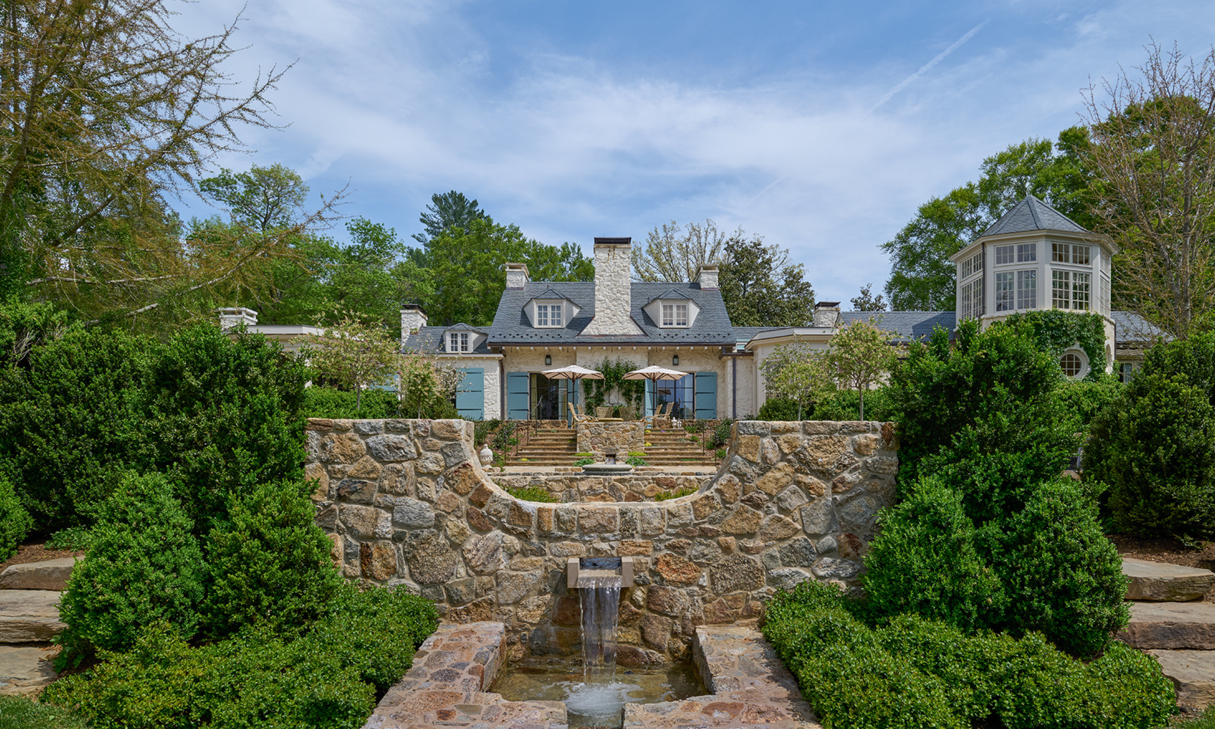 Large property with stone water feature and rill in foreground
