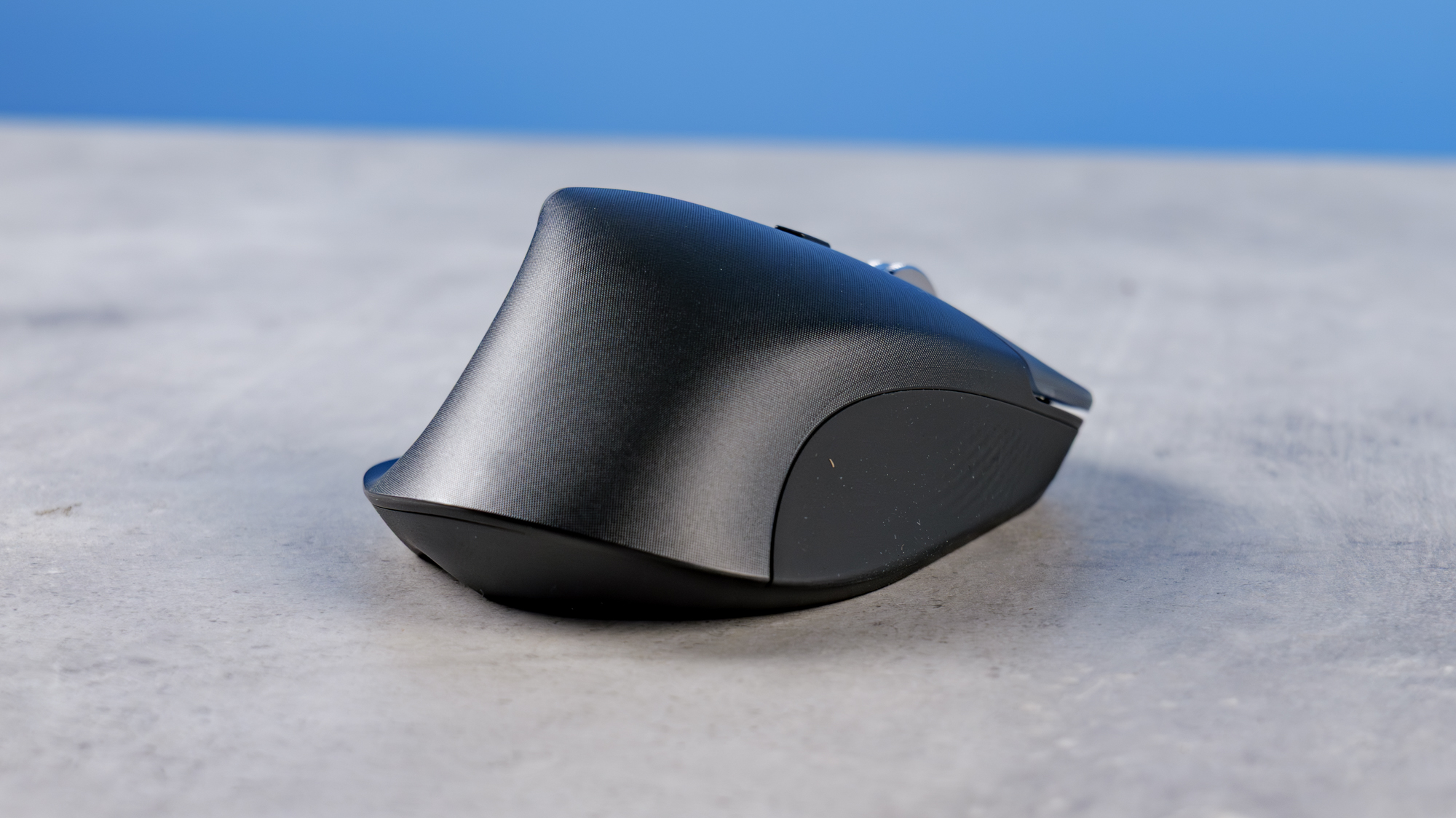 A photo of the Logitech MX Master 4 on a stone surface with a blue background