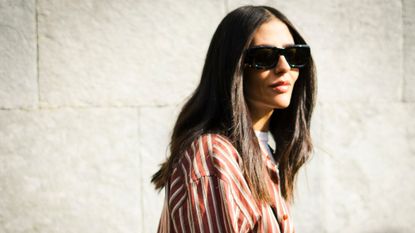 A woman with chocolate hair wearing sunglasses and a striped shirt