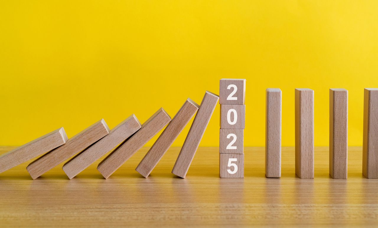 wooden domino blocks falling to a 2025 block