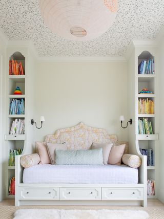 Girls bedroom with built in bookcases and wallpapered ceiling