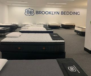 Inside the 3Z Brands showroom: a row of mattresses against a white wall with 'Brooklyn Bedding' written on it.