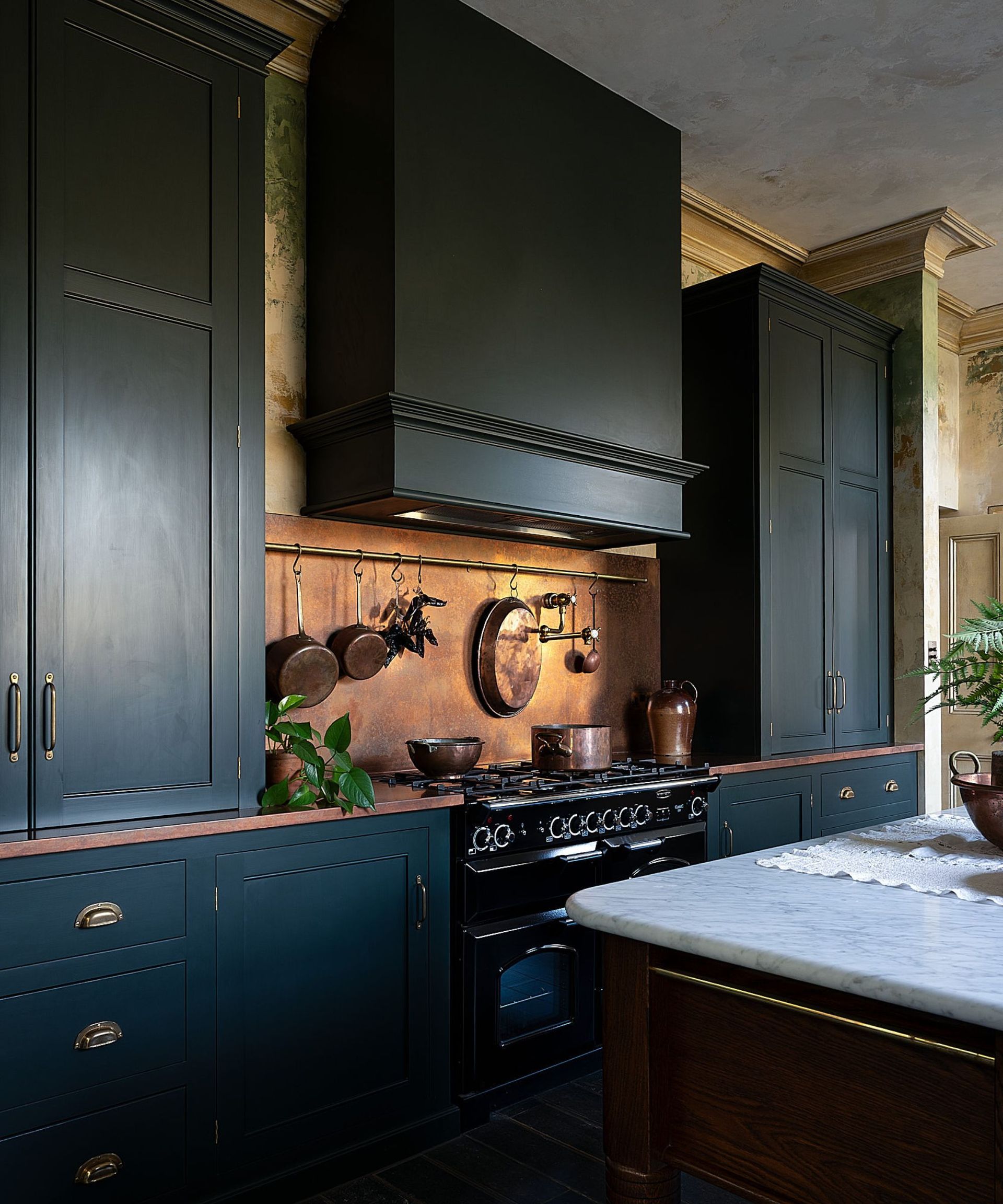 A dark green kitchen with copper countertops and backsplash and a freestanding range cooker