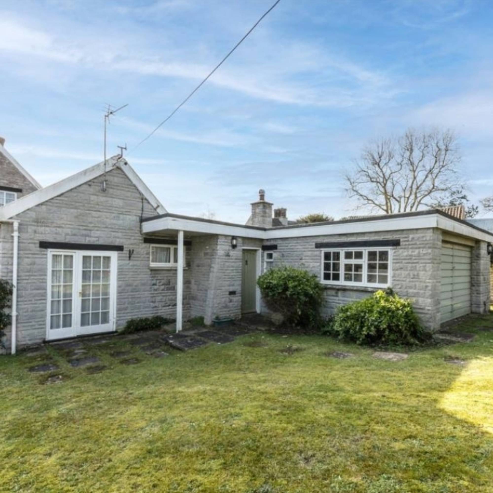 stone extension with white windows and lawn