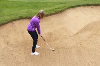 Touching sand in bunker with golf club