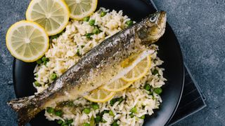 roasted trout on bed of rice with peas and lemon slices