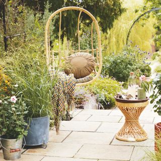 Boho-style patio with a hanging egg chair and table with potted plants