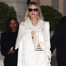 Rosie Huntington steps outside in Paris wearing a white suit with a white knit around her neck.