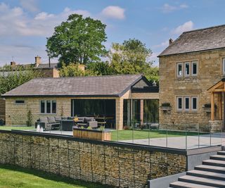 A contemporary stone sextension attached to a stone cottage with an adjoining bridge corridor