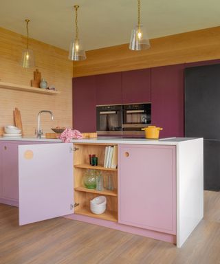 A pink peninsula in a wooden kitchen scheme with pink and yellow accents.