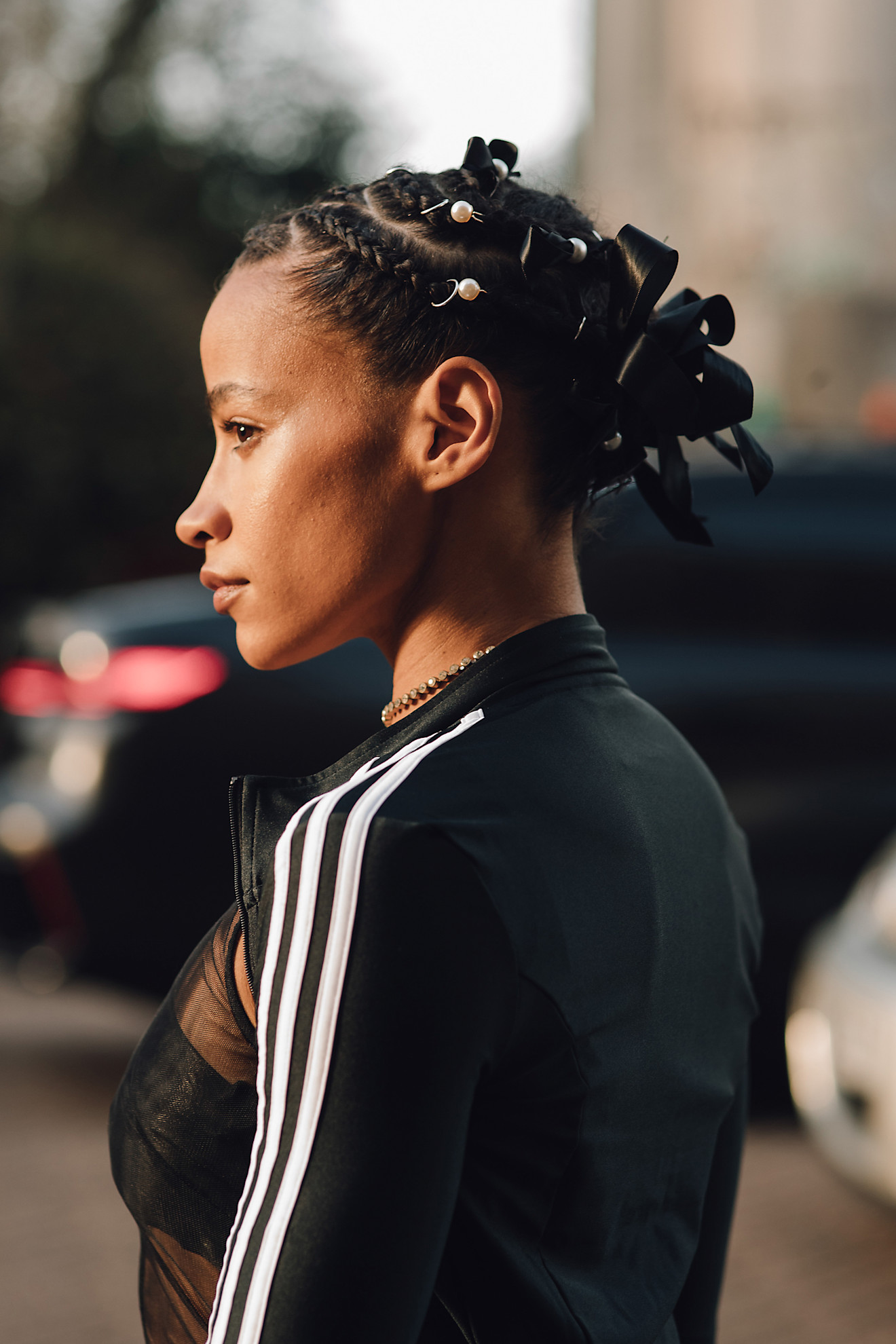 A woman with a braided updo, decorated with pearl rings and black ribbons