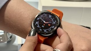 Galaxy Watch Ultra on a person's wrist with an orange strap