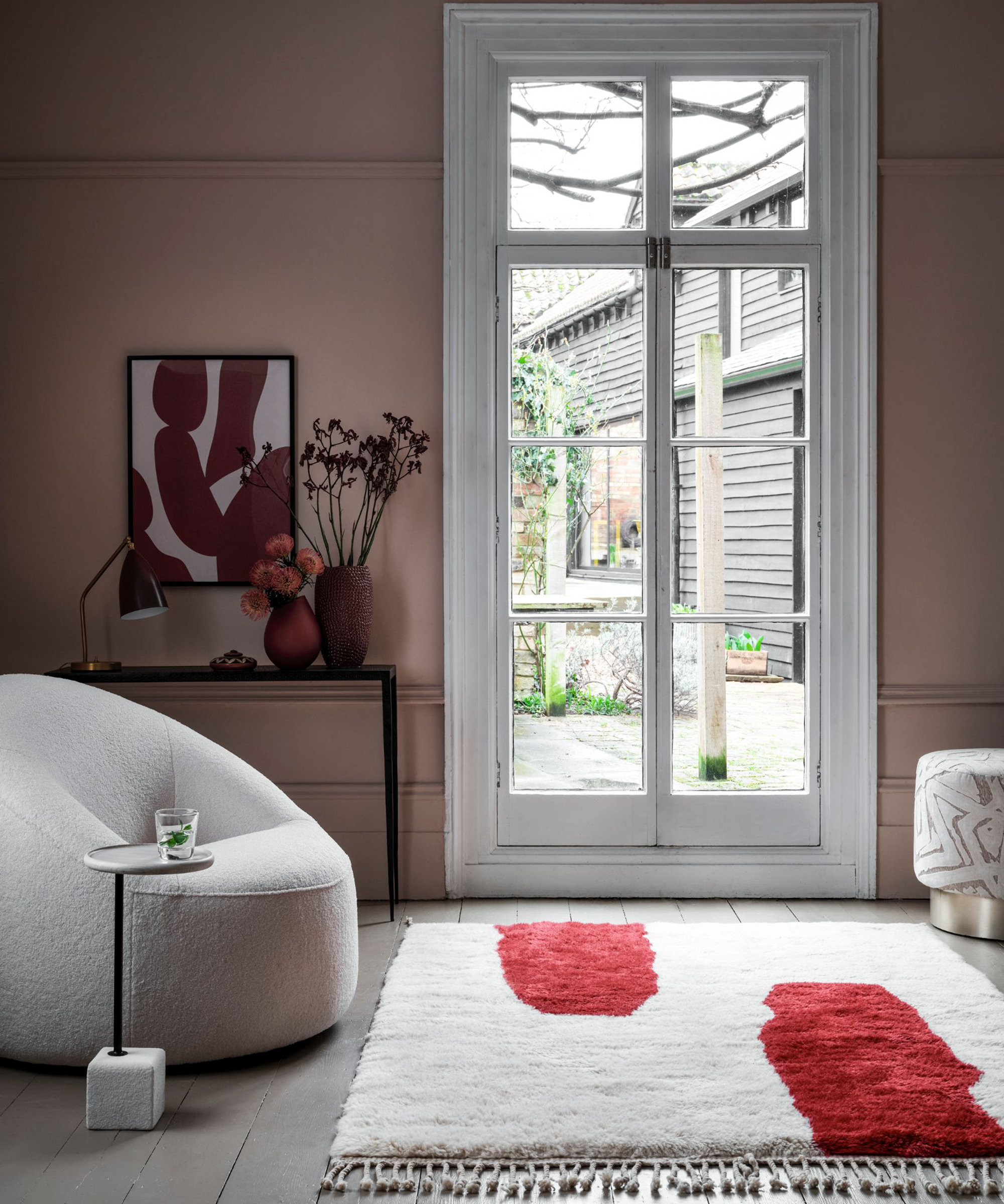 A modern living room idea by Cosy Coco with abstract wall art, dusty pink walls and patterned rug