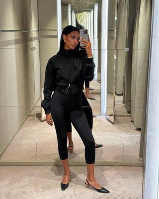 Model Jasmine Tookes wears cropped capri leggings with black slingback flats and cropped jacket while taking mirror selfie.