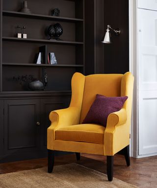 yellow armchair on a rug set against dark shelving