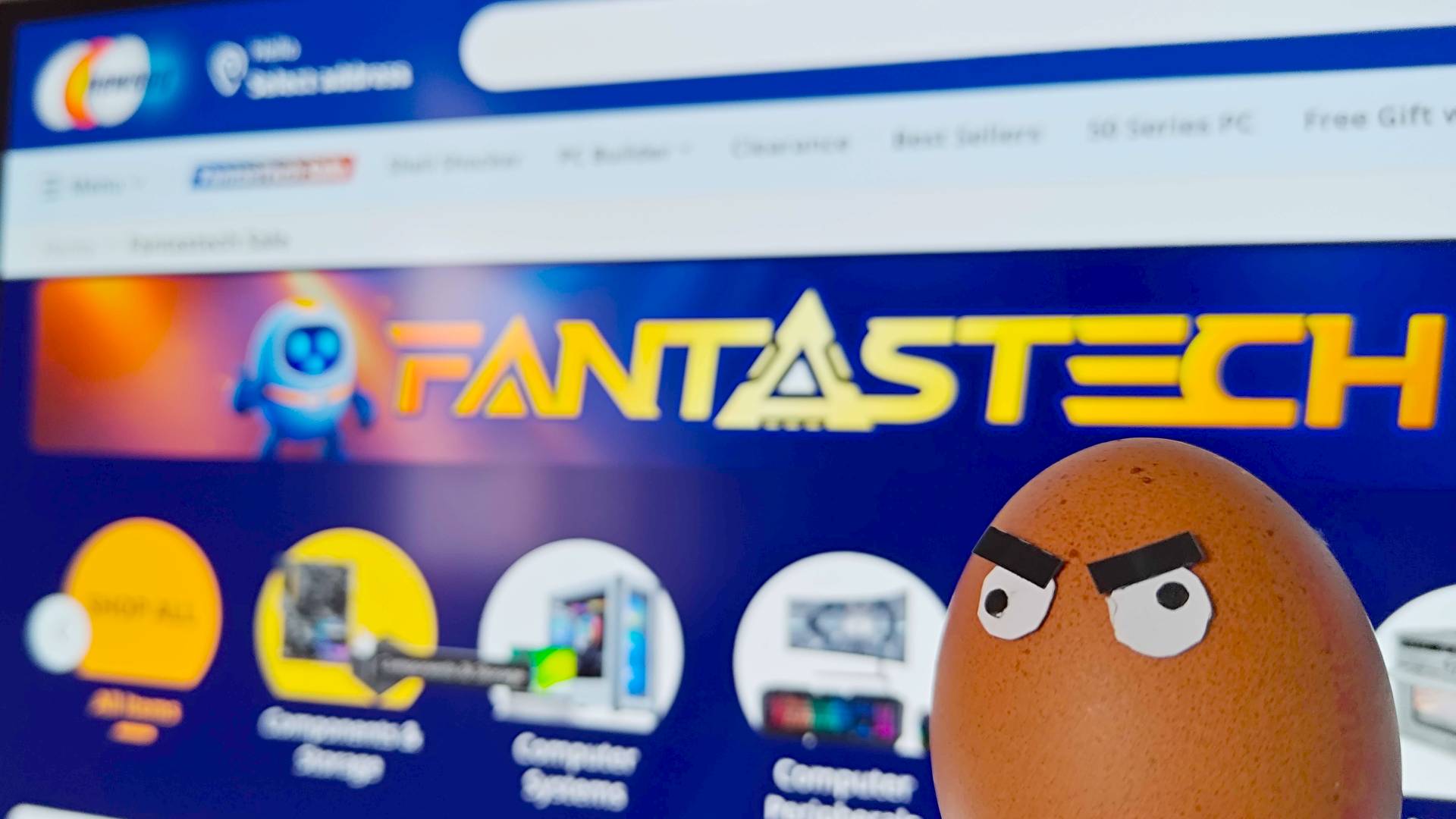 Close up of Newegg FantasTech sale page with egg wearing angry eyes in front of screen.