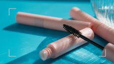 two tubes of mascara on a blue backdrop to illustrate the debate between brown vs black mascara 