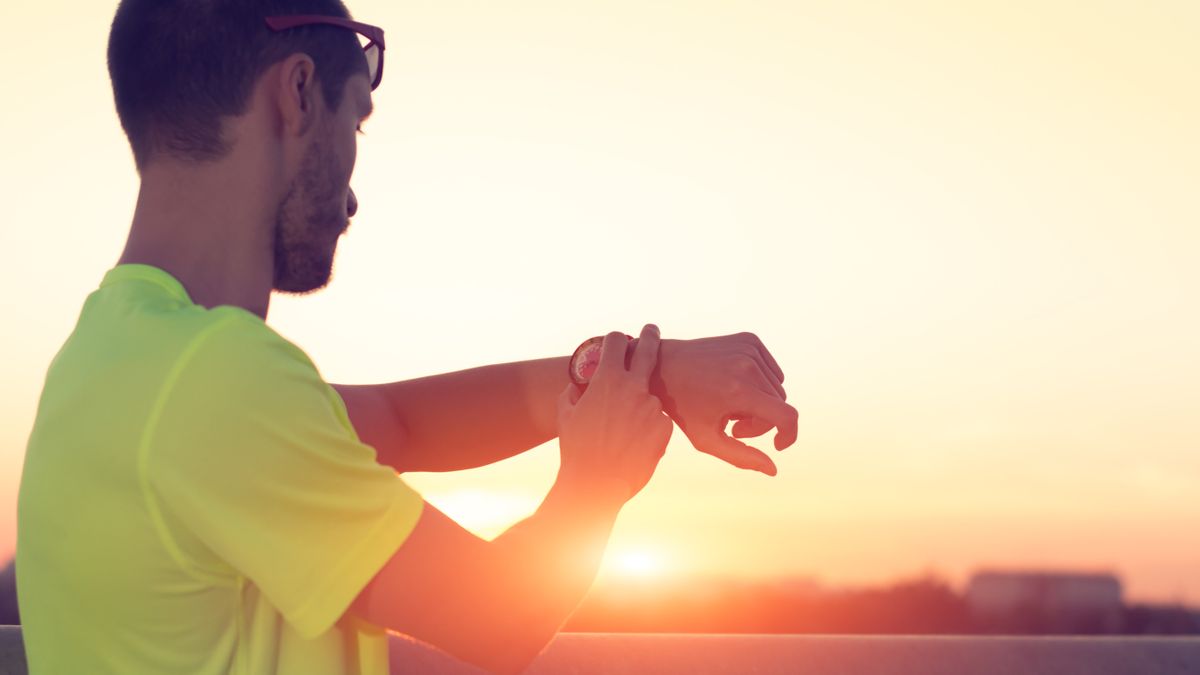 Man using running watch at sunset