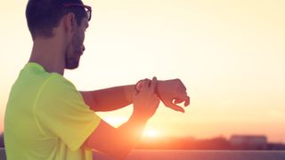 Man using running watch at sunset