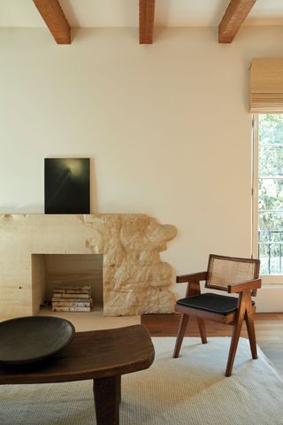 Living room with exposed beams and travertine stone fireplace surround