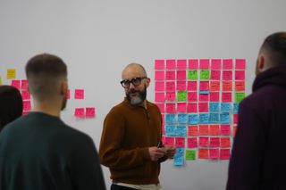 person standing in front of a load of sticky notes on a whiteboard