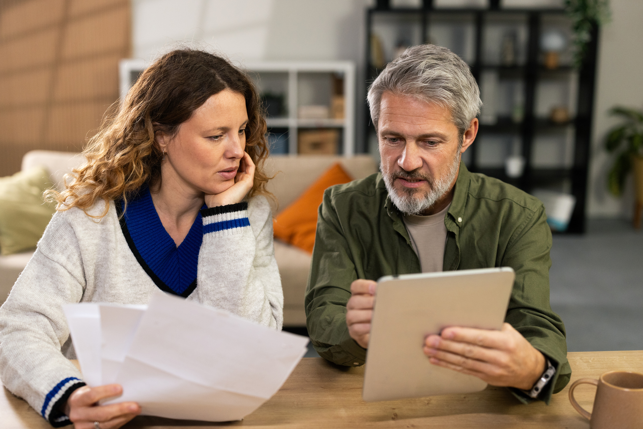 Mature couple discussing budget and bills, feeling worried about their financial future