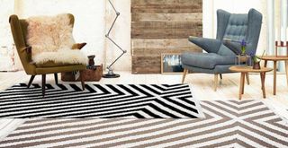 living room with two large striped rugs layered to demonstrate a new flooring trend for 2023