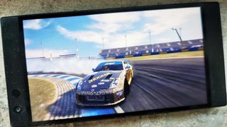 A phone displaying gameplay from GRID Autosport