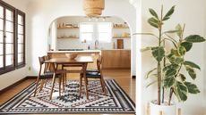 An Aztec-inspired rug on Amazon from Ruggable in neutrally-decorated kitchen-diner with potted houseplant in foreground