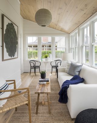 white screened in porch with a white sofa and sisal rug