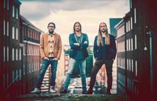 Von Hertzen Brothers standing on a wall with some residential apartments behind them