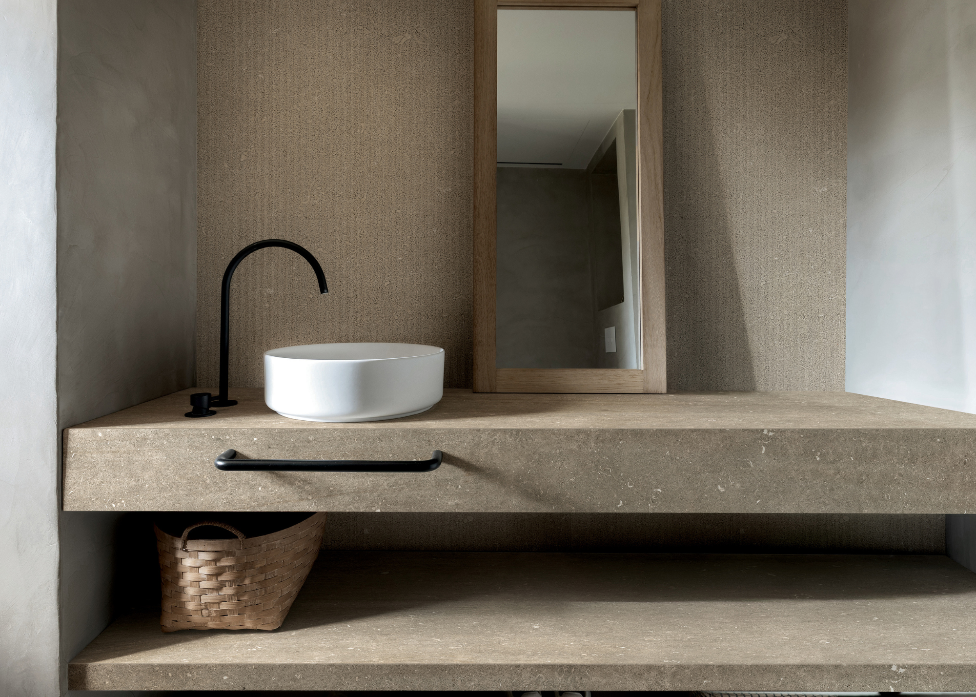 cork tiled bathroom vanity with a sink on top and black hardware and a mirror on top