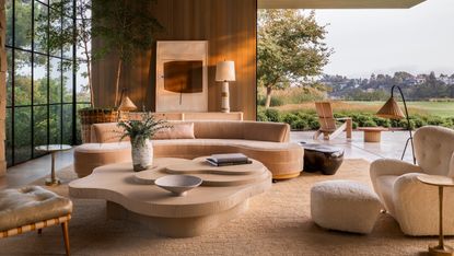 Pink-beige curved couch in large living room with corner opening doors
