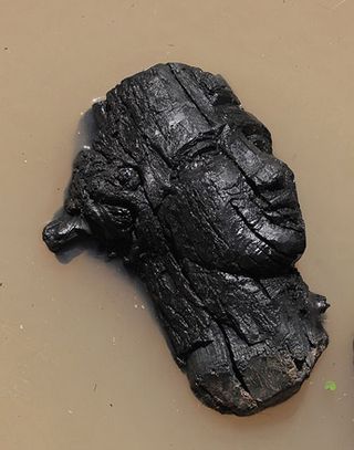 Face carved on dark wood