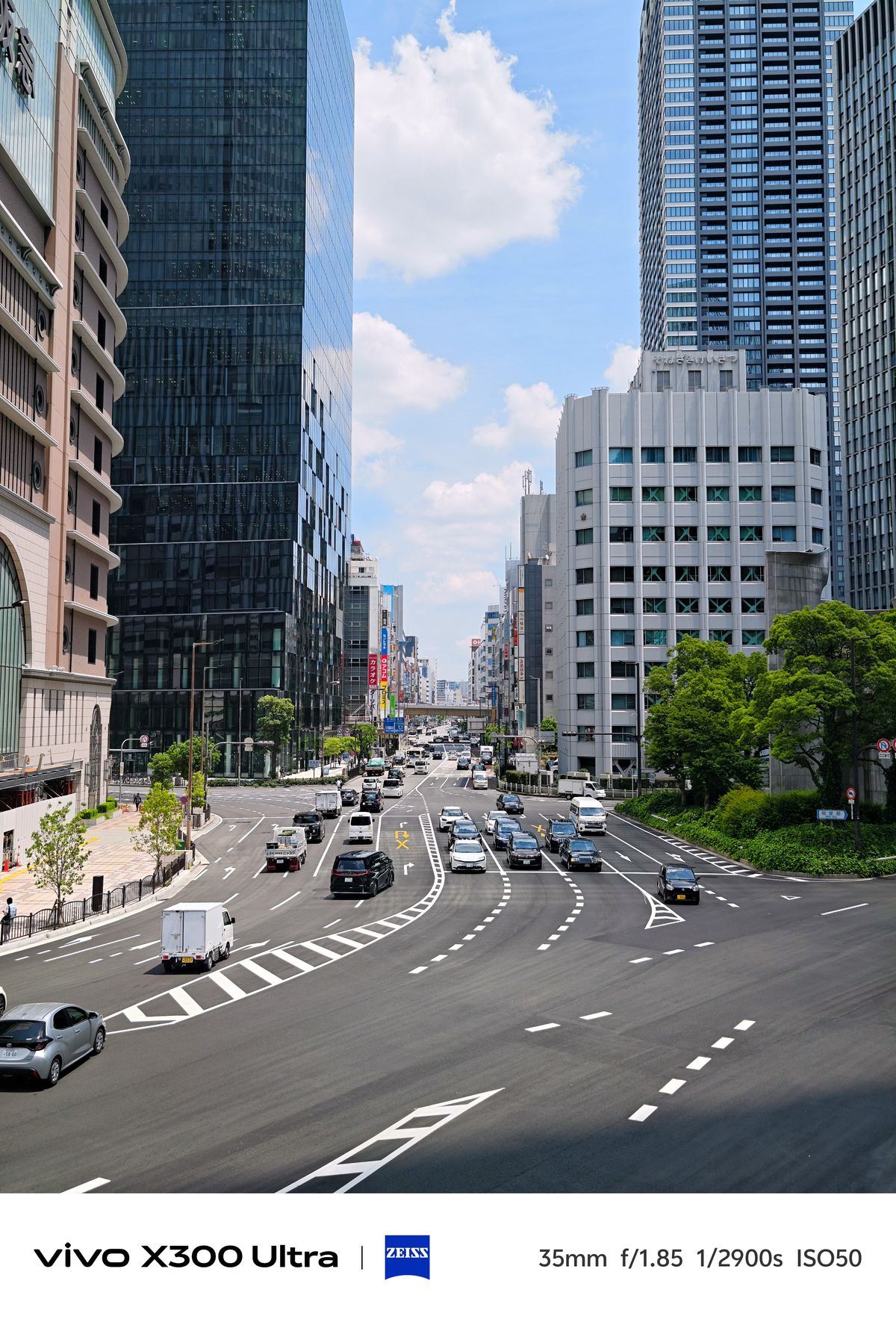 High-angle view of a wide, multi-lane city intersection surrounded by glass office skyscrapers.