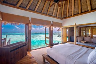 A bedroom in a thatched-roof villa at Gili Lankanfushi in the Maldives