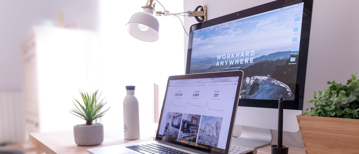 A MacBook and Mac displaying websites and images in a bright office setting