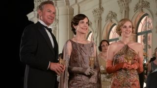 Hugh Bonneville, Elizabeth McGovern, and Laura Carmichael drinking together at a party in Downton Abbey: A New Era.