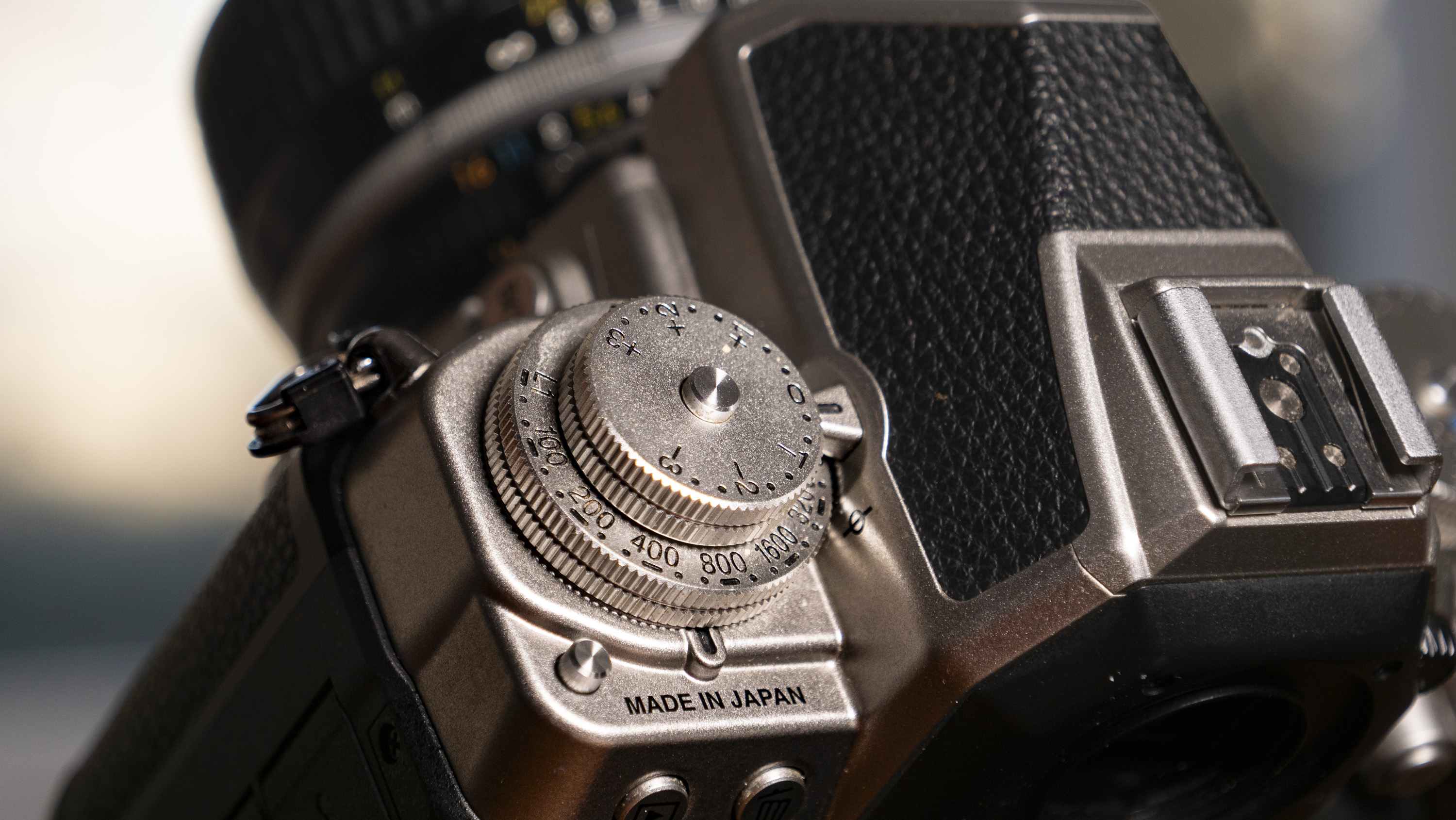 Nikon Df DSLR camera on a wooden surface by large window, with dusk light